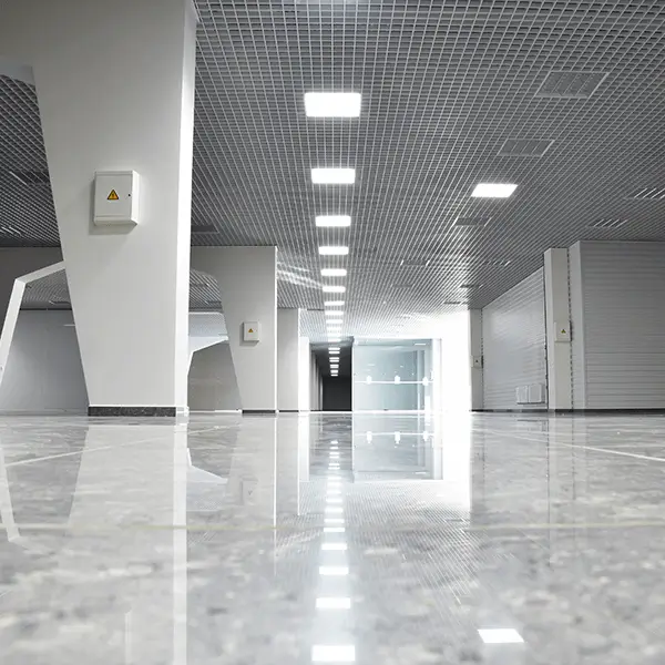A spacious, modern interior with polished floors and bright ceiling lights, featuring a minimalist design and open pathways. The setting appears to be part of a contemporary building.
